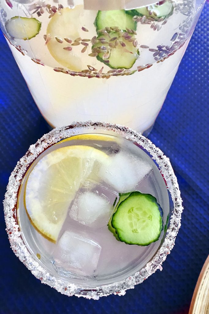 Cucumber Ginger Lavender Lemonade- glass with lemonade and pitcher in the background
