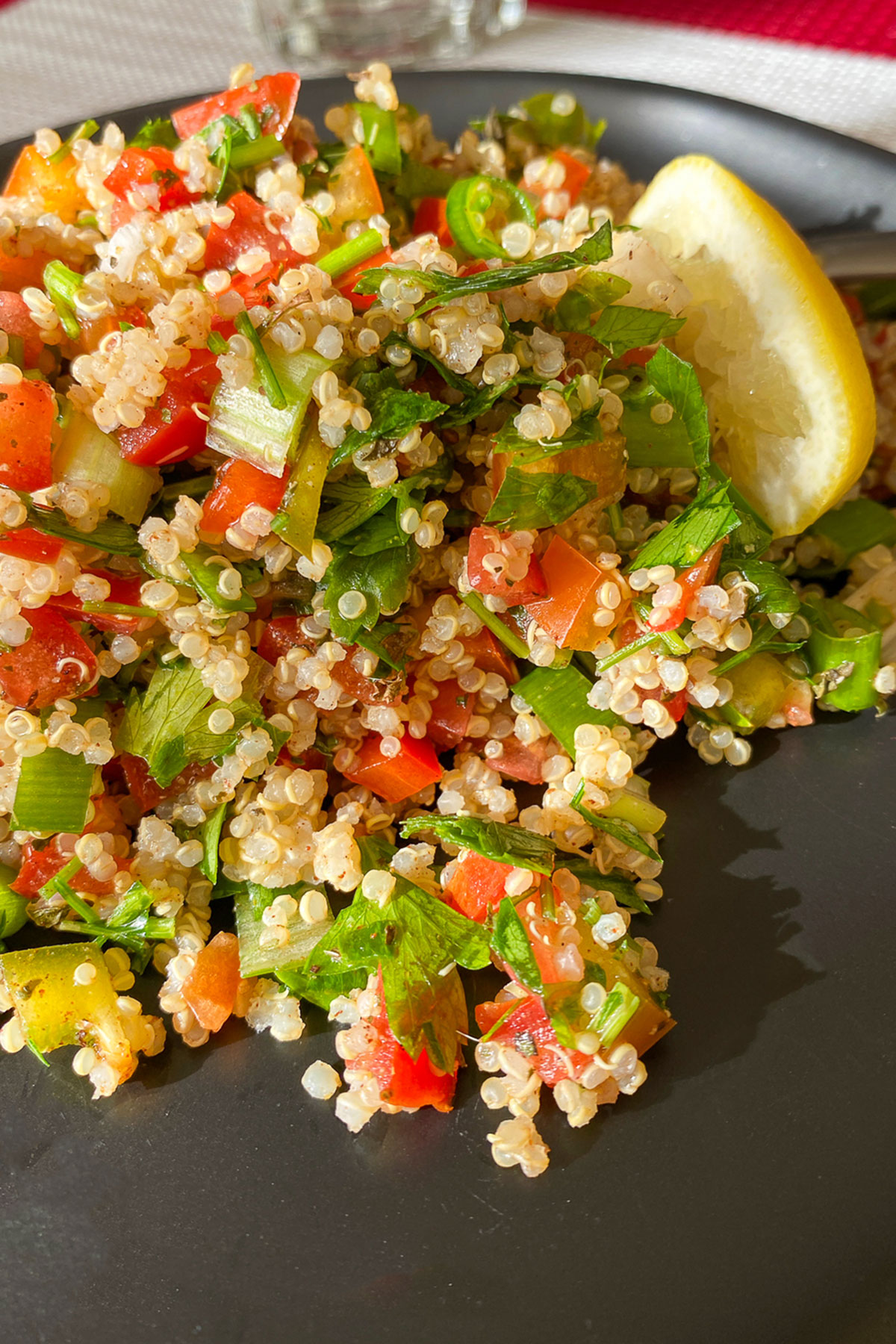 This quinoa tabbouleh salad uses beautiful, fresh ingredients that are easy to put together. Delicious and also gluten free. Delicious Quinoa Tabbouleh on black plate with lemon
