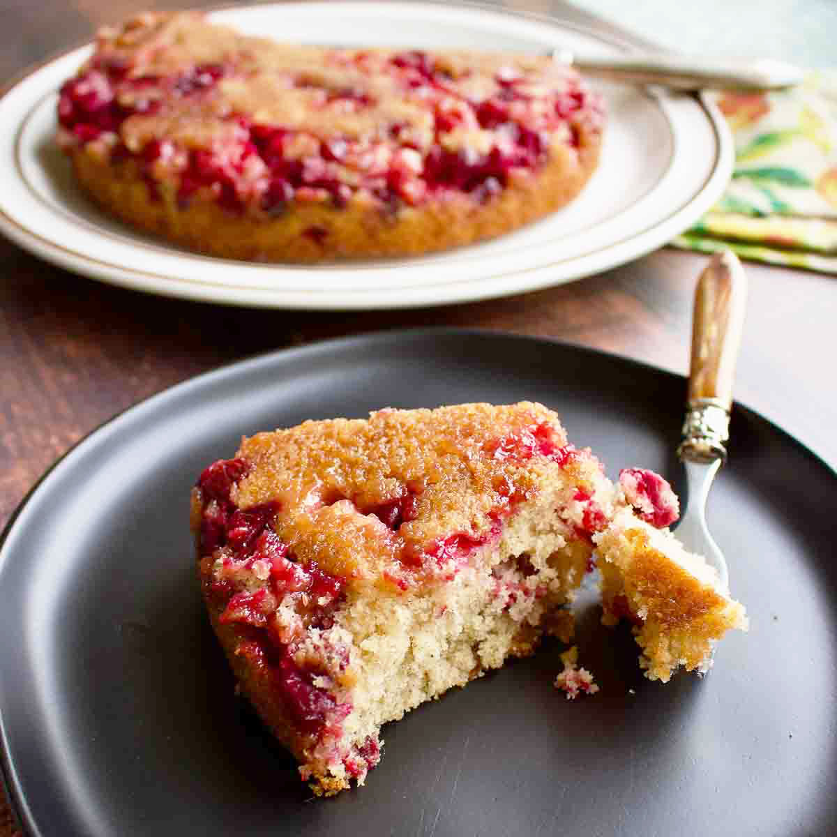 Slice of Cranberry Upside Down Cake on black plate.