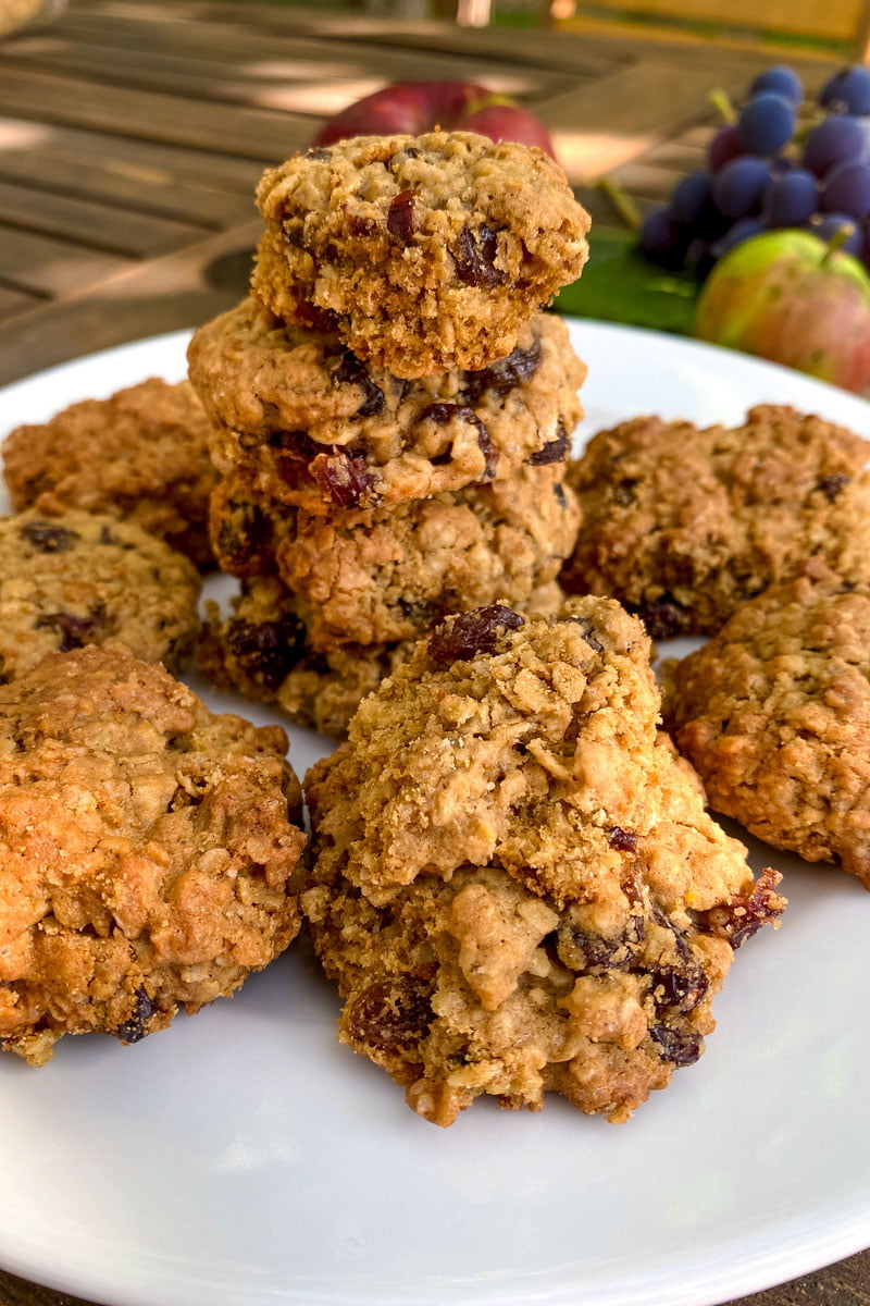 Oatmeal raisin cookies on a plate with apple in the background