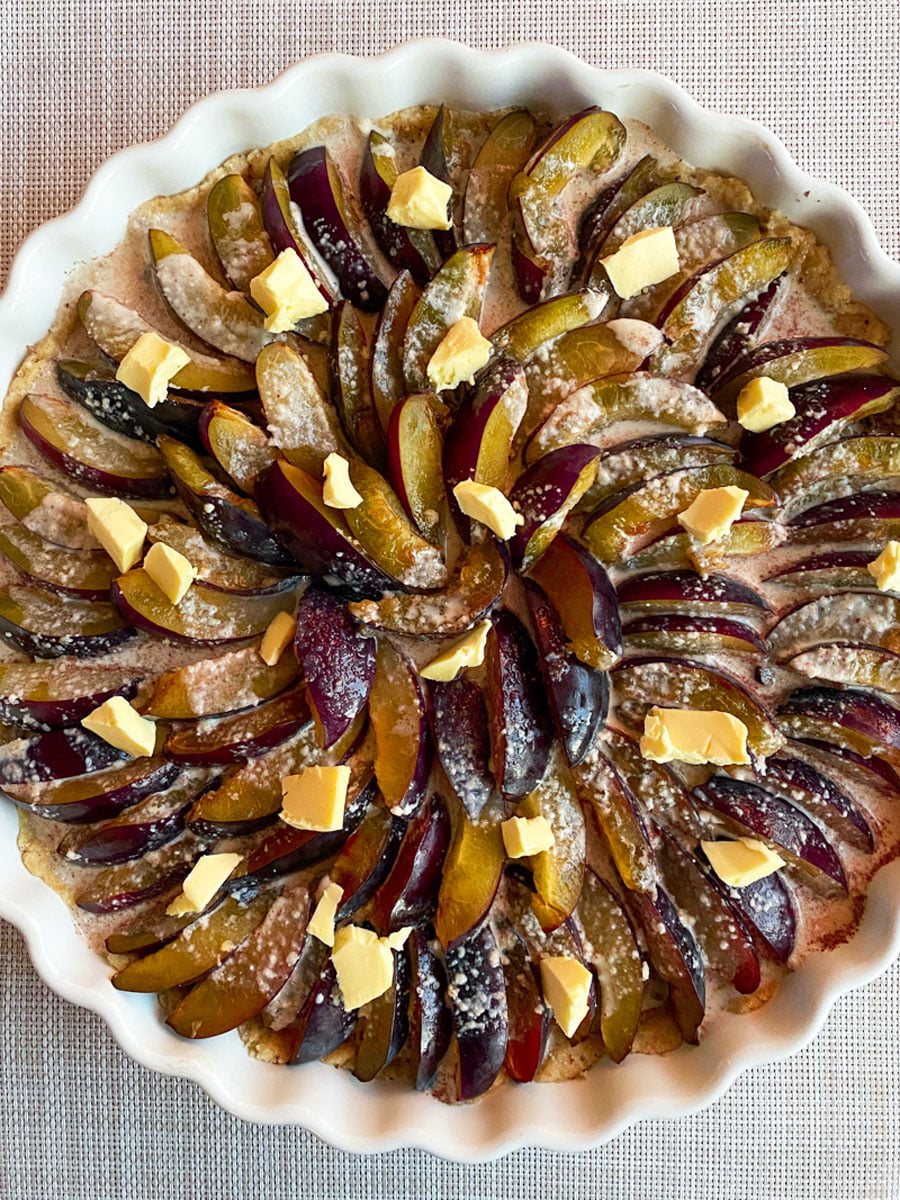 Plum tart - plums on the crust with pieces of butter on top