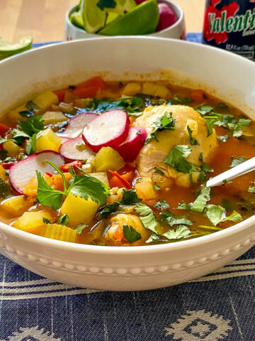 Caldo de Pollo topped with radishes in a white bowl.