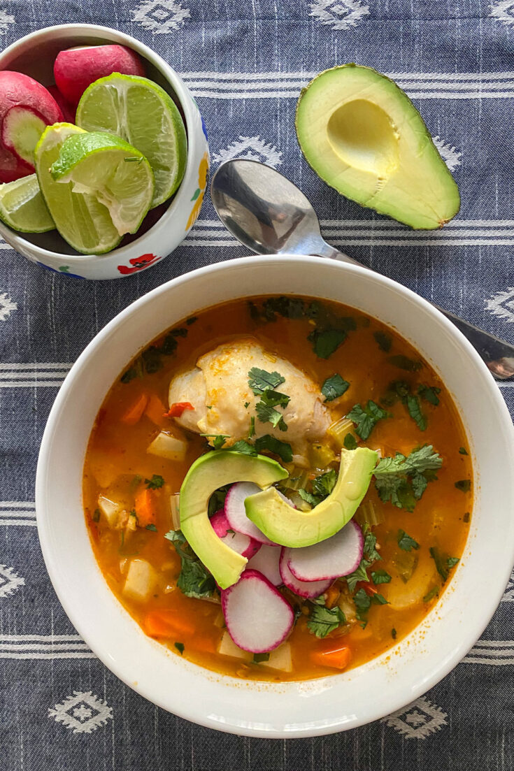 caldo de pollo served on white bowl with avocado (Caldo de Pollo Or Chicken Soup Mexican Style)