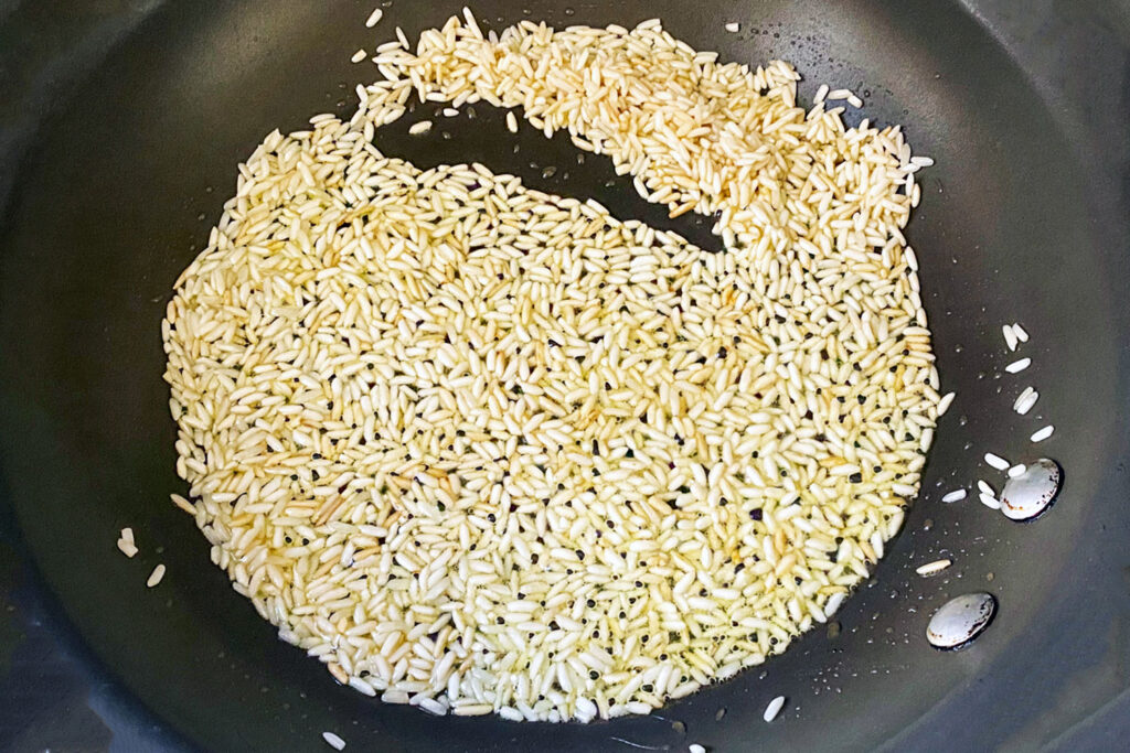 rice cooking with oil in the pan(Caldo de Pollo Or Chicken Soup Mexican Style)