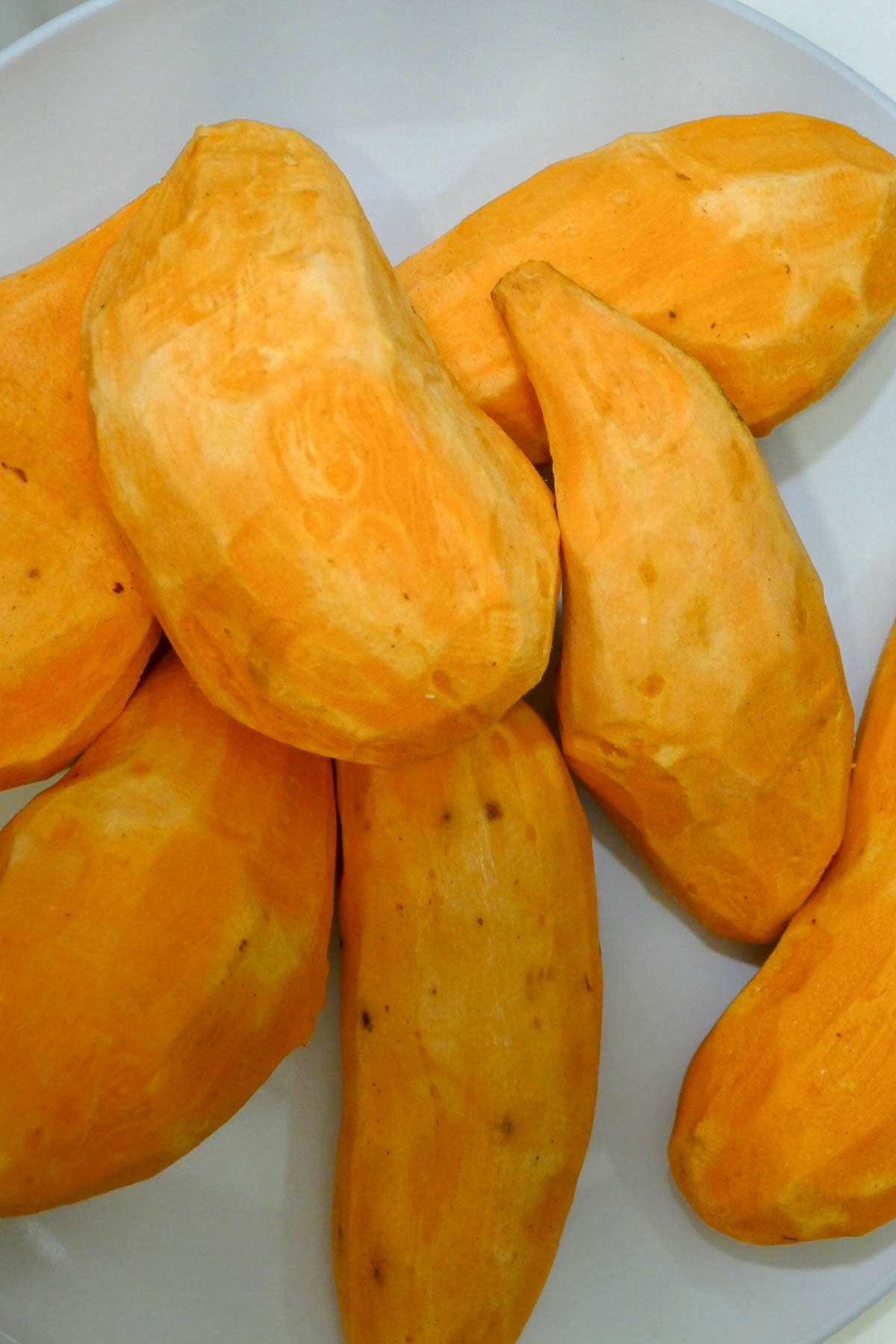 Peeled sweet potatoes on a plate.