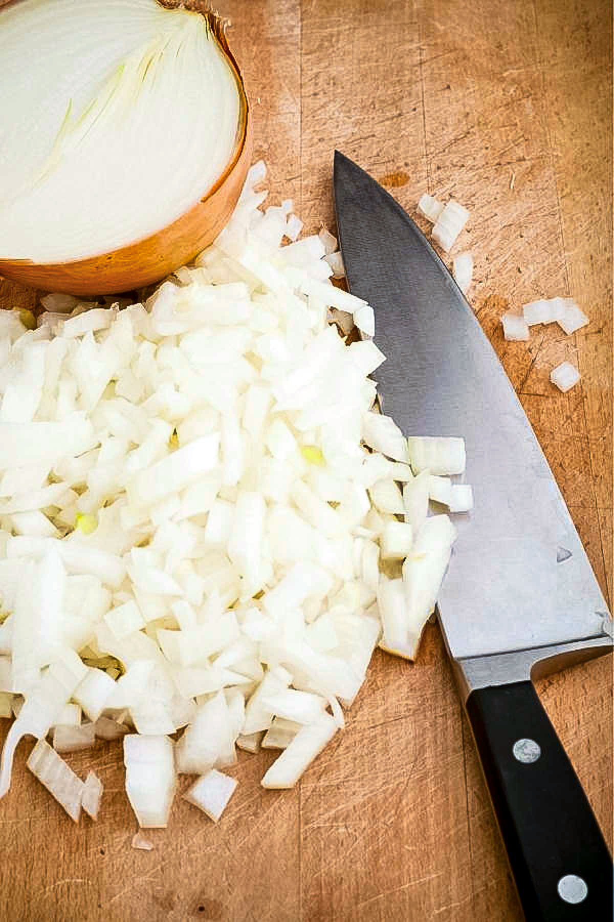 Chopped onion on a cutting board with knife.