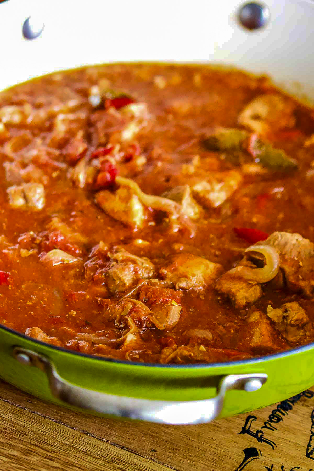 Hungarian Goulash in a green Dutch oven on wooden board.