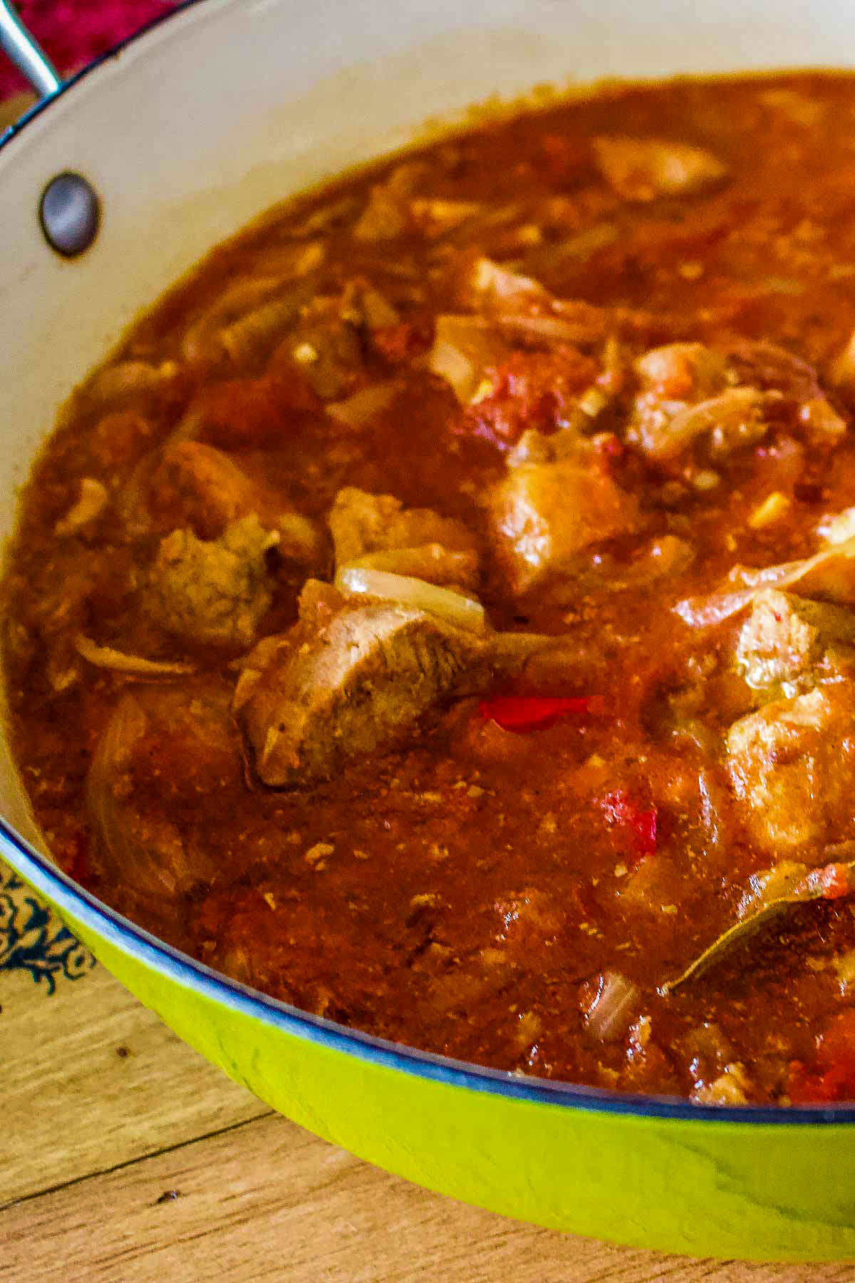 Hungarian Goulash in a green Dutch oven sitting on a cutting board.