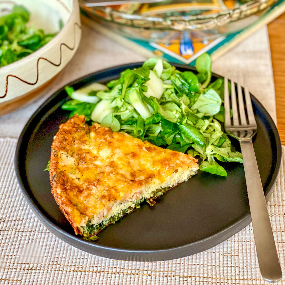 Salmon and Spinach Quiche slice on plate with greens square photo0