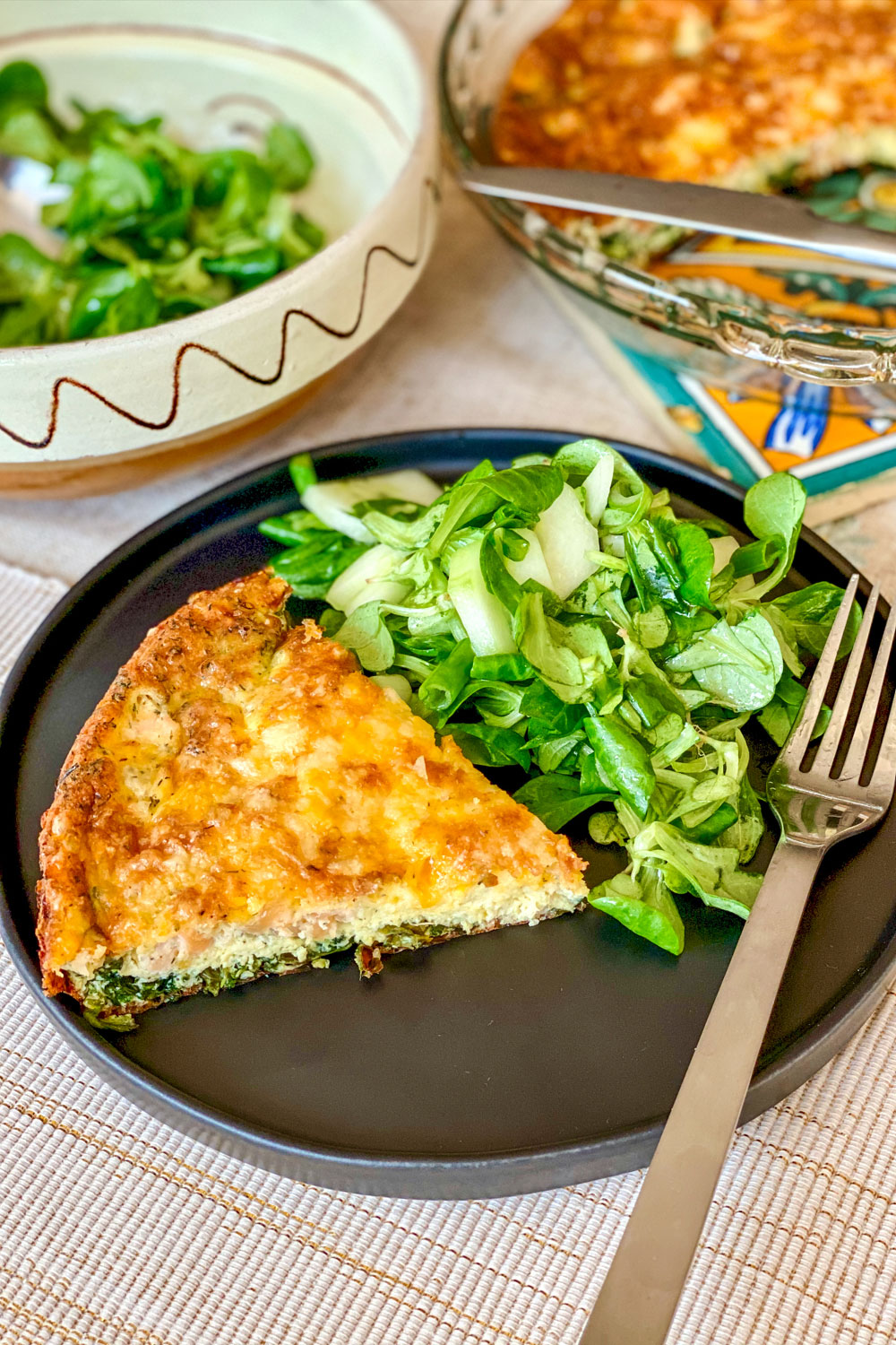 Salmon and Spinach Quiche slice on plate with greens0