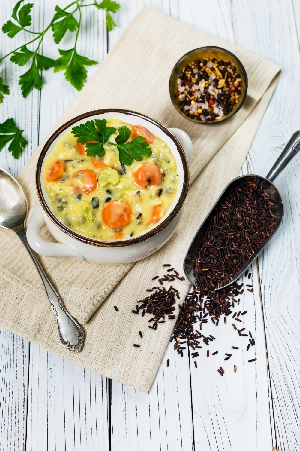 wild rice soup in a white pot with wild rice on table