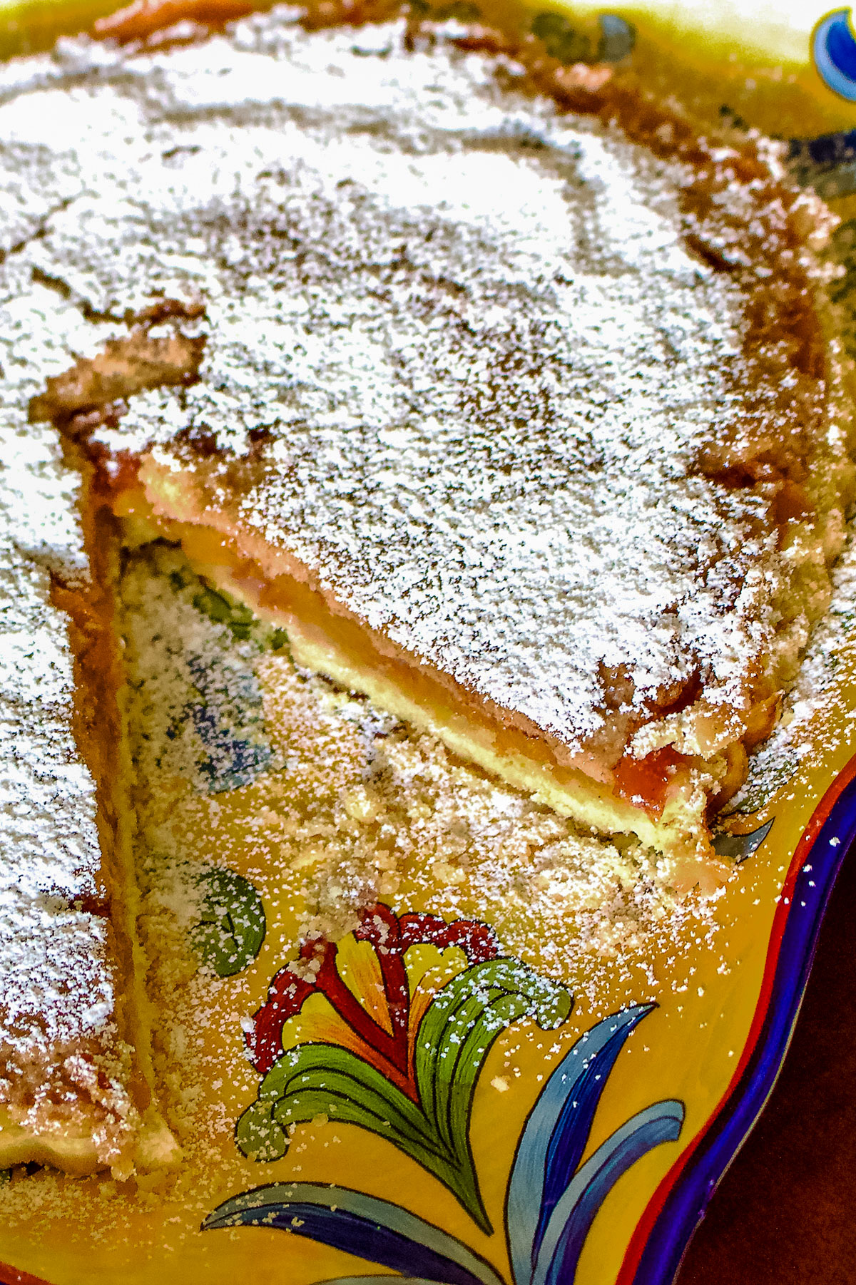 German Peach Kuchen- a Transylvanian dessert made with peaches, custard and a shortbread crust. Delicious, easy to make and perfect for summer. Peach Kuchen on a yellow platter0