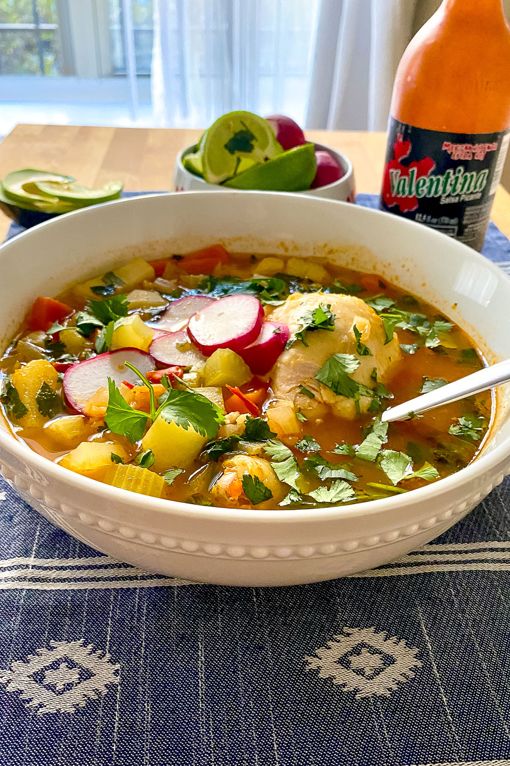 Caldo de Pollo Mexican Chicken Soup on table with salsa Valentina in the background0