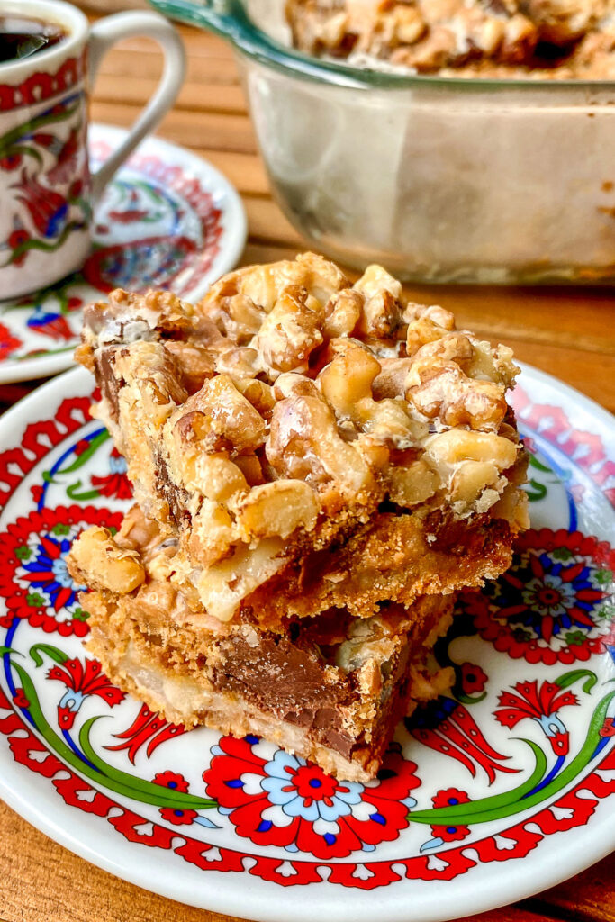 Seven Layer Bars Two pieces stacked on white and red plate.
