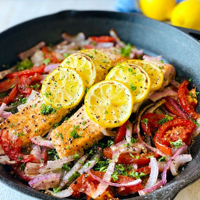 Easy Baked Salmon in skillet lemon in background