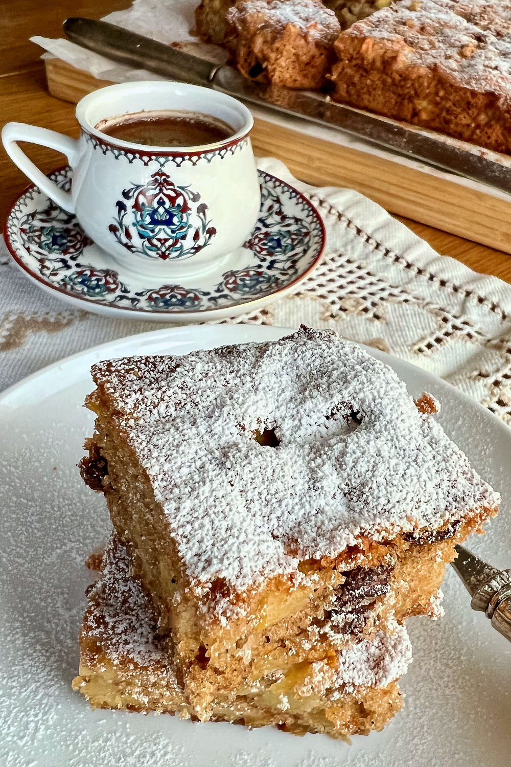 Baked Apple cake bars on plate with coffee in the background