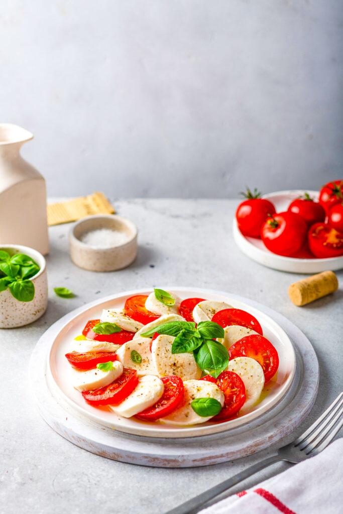 Caprese Salad with a plate of tomatoes in the background