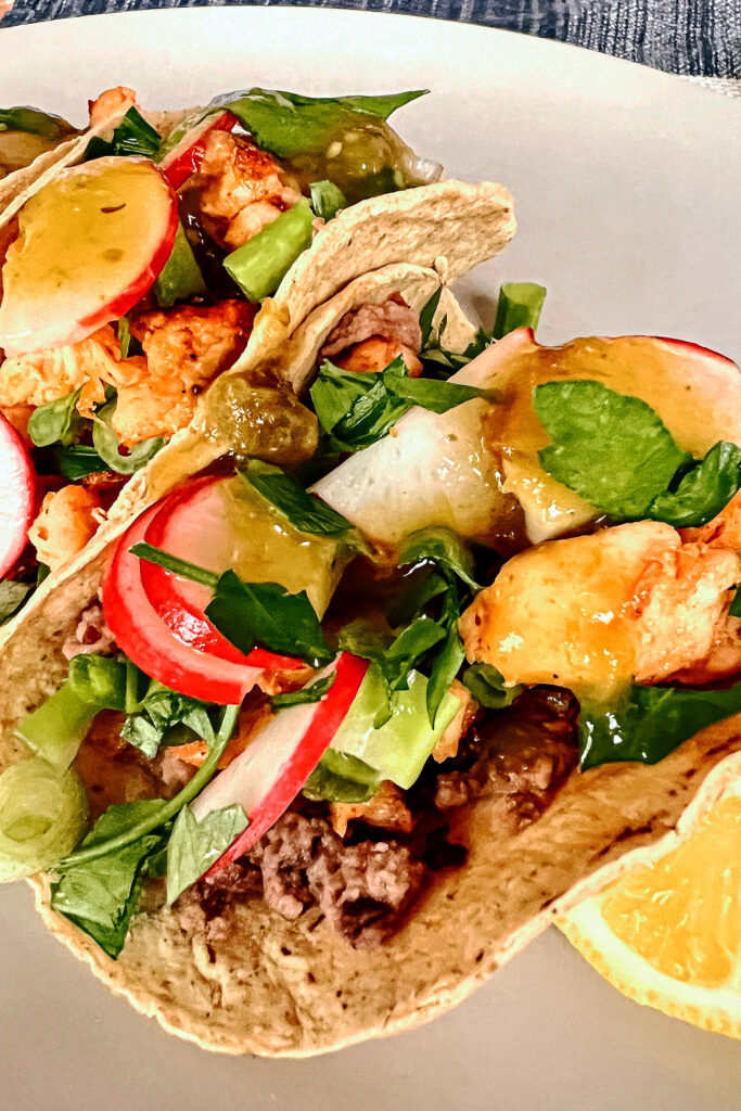 Chicken taco with cilantro and radishes on a white plate
