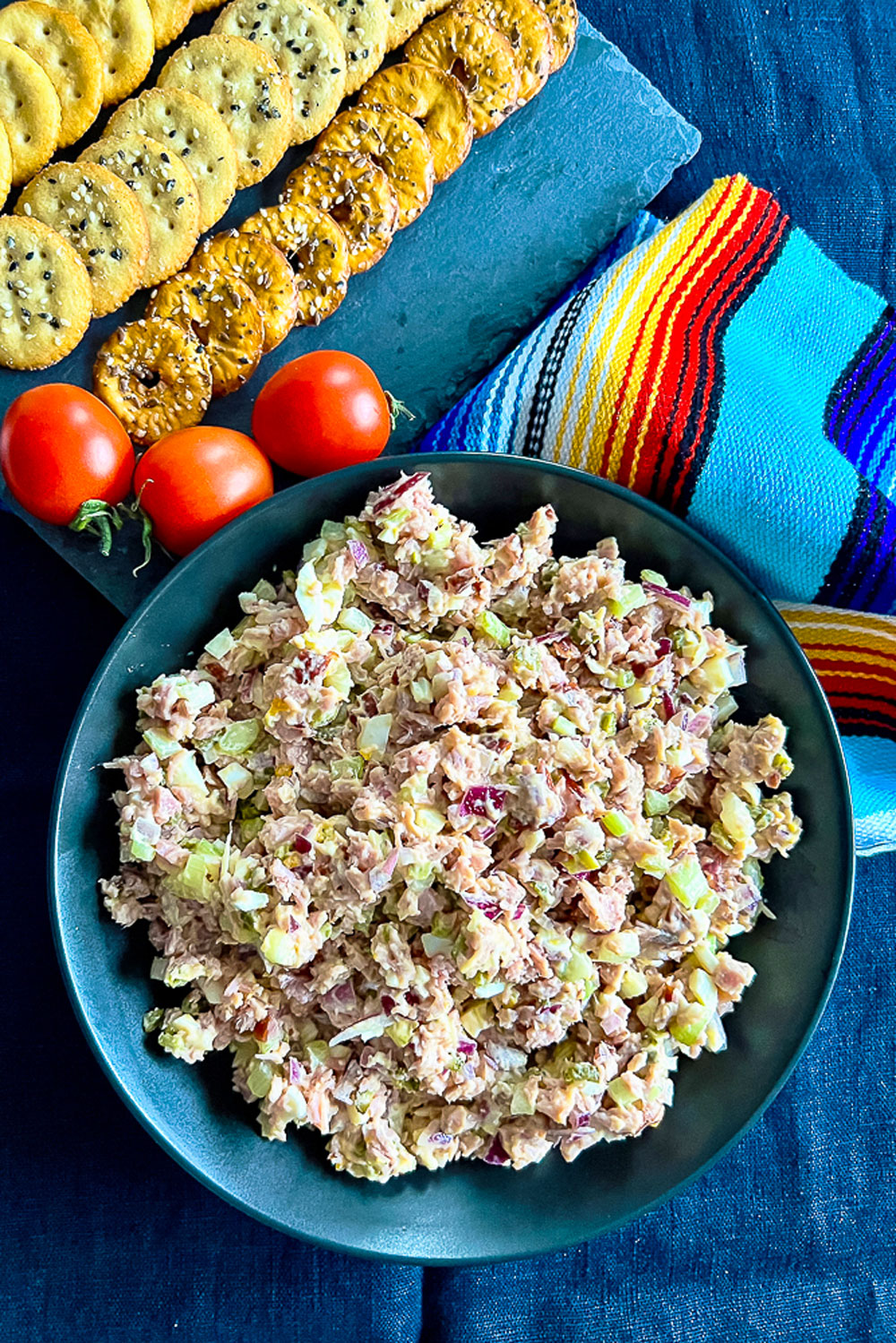 Ham salad in a bowl with tomatoes and crackers in the background