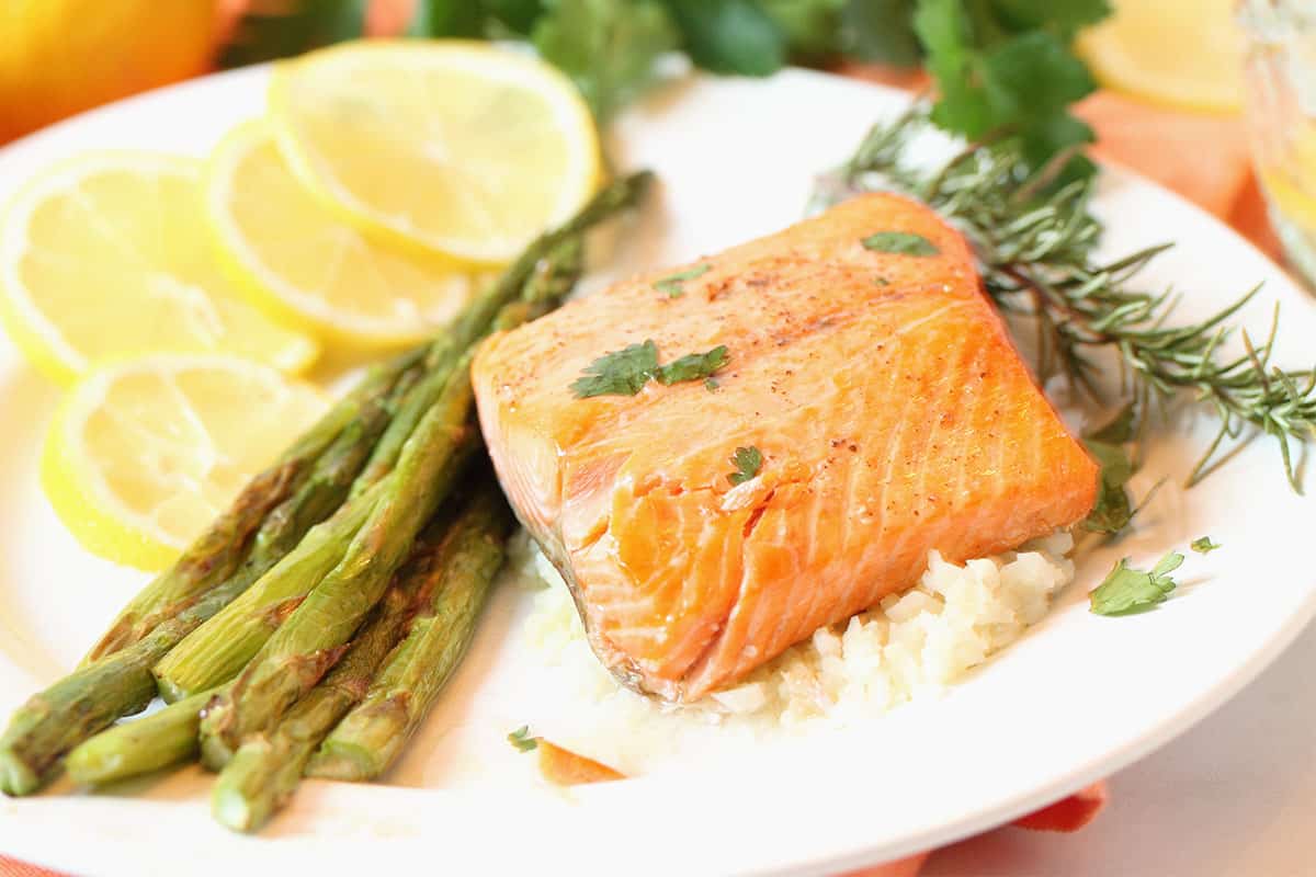 Salmon dinner with asparagus and lemon slices on white plate wide