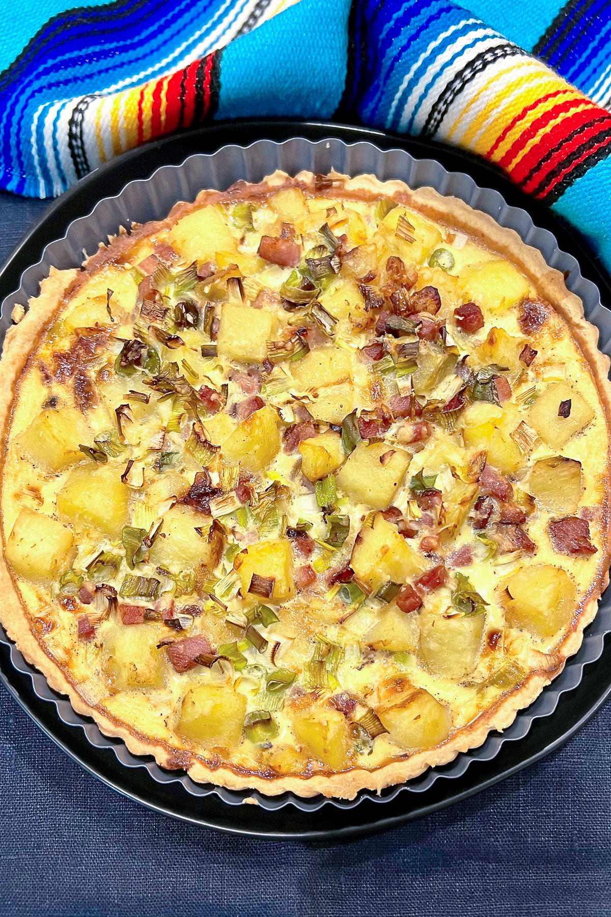Ham and potato quiche with colorful kitchen towel0