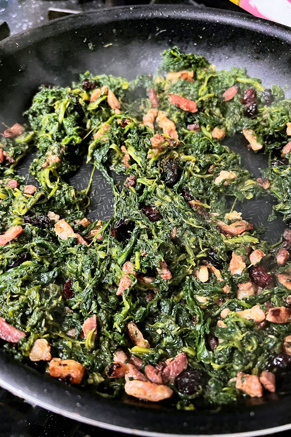 Spinach with bacon in a skillet.