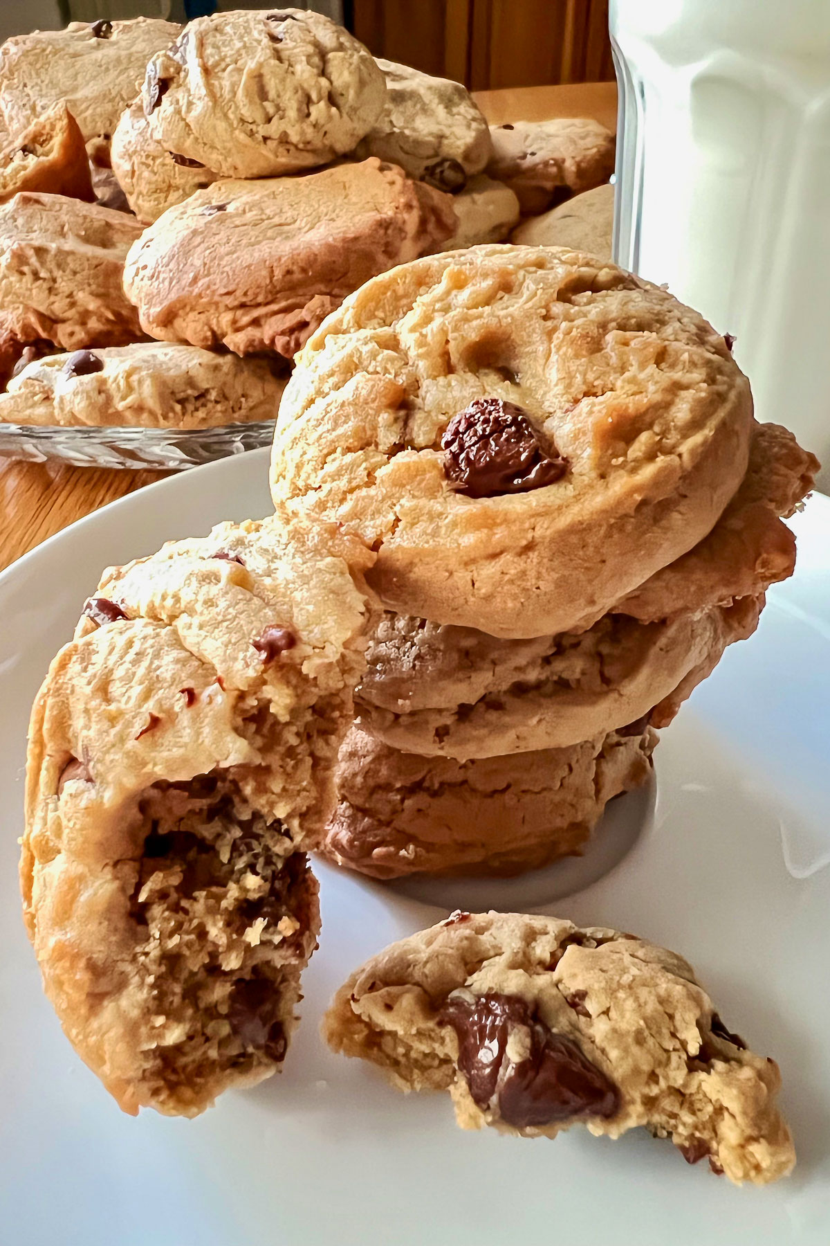 Ghirardelli chocolate chip cookies on plate with glass of milk in the background0