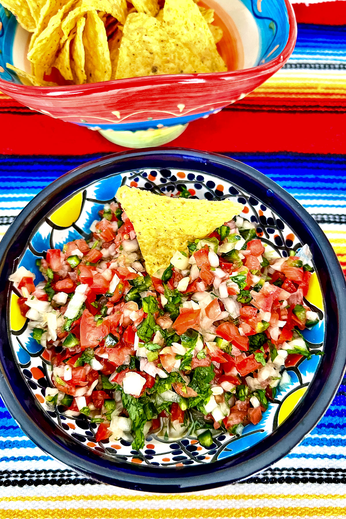 Mexican Pico de gallo in a bowl with corn chips in the background
