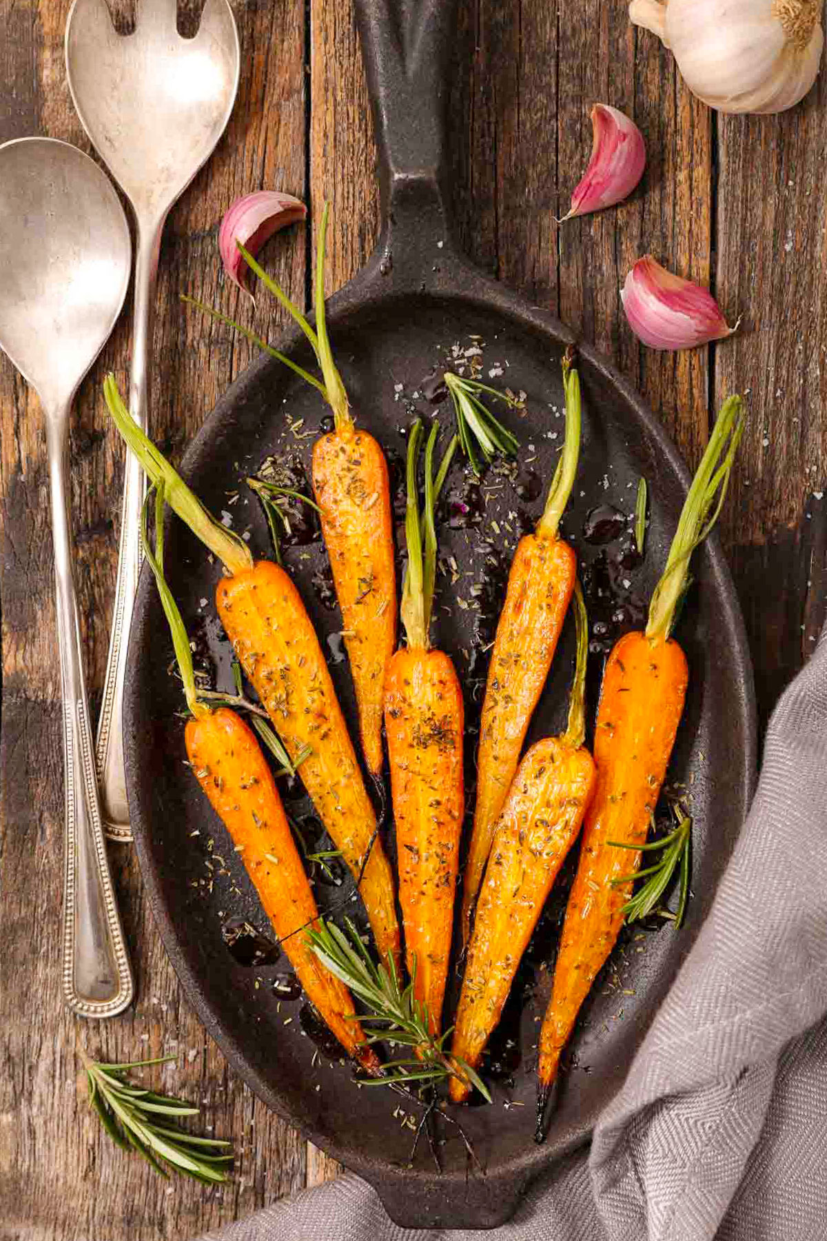 Roasted Carrots on Cast Iron Pan with serving spoons.