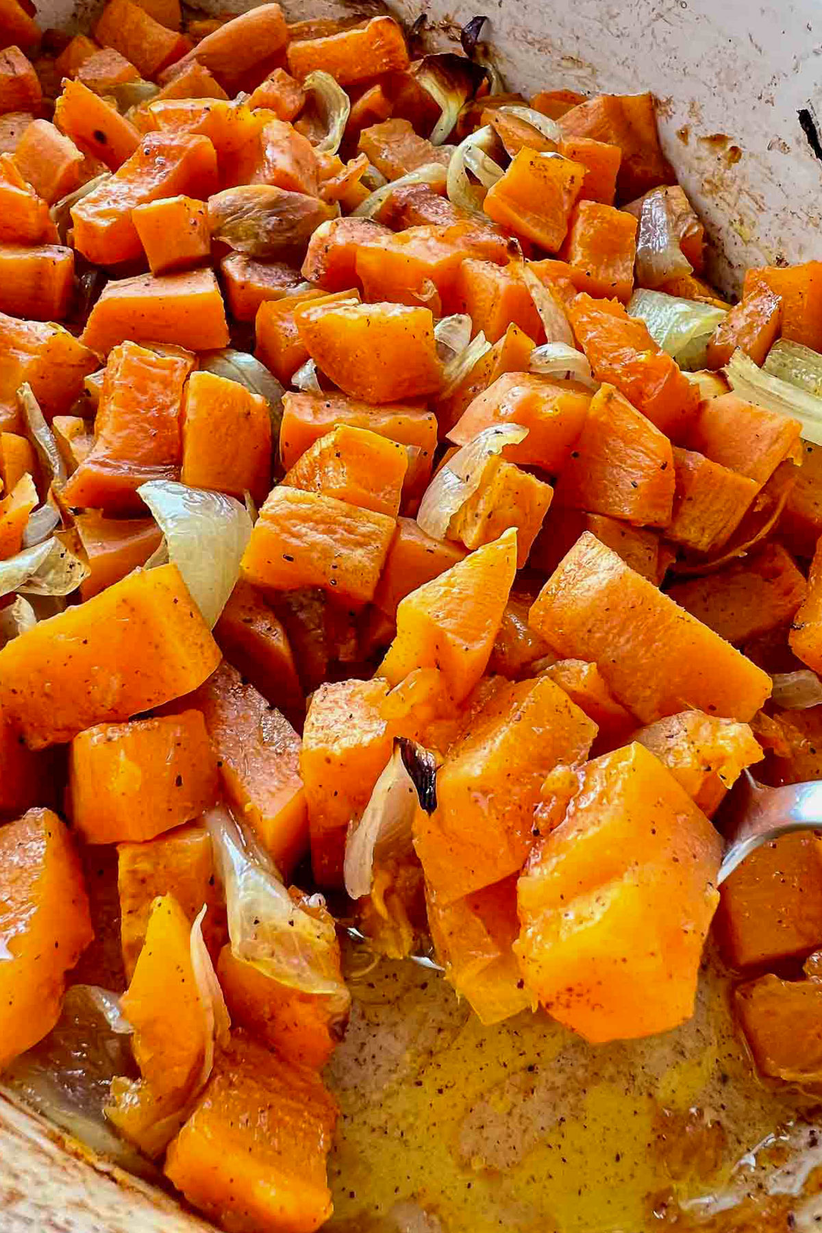 Roasted Sweet Potatoes in a baking dish with spoon.