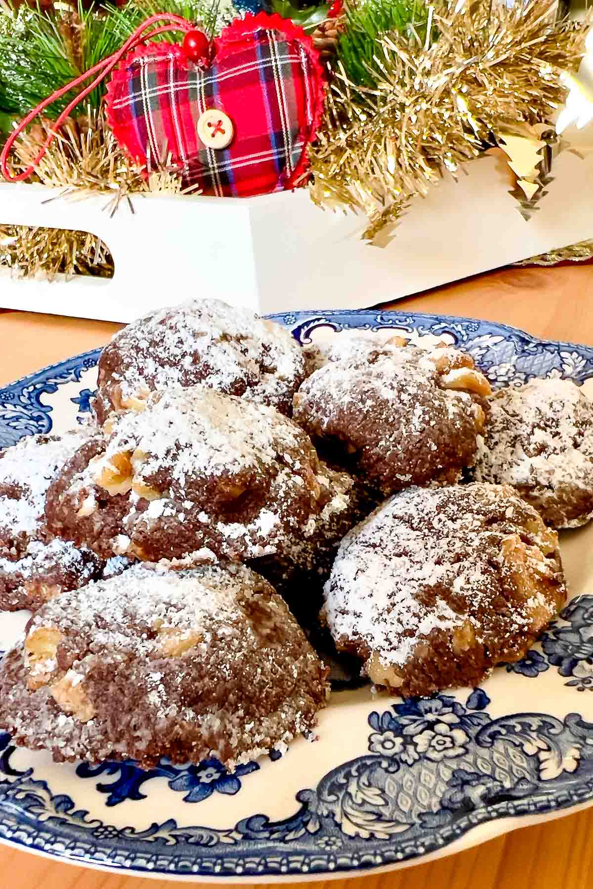 Mocha Walnut Butter Cookies on white and blue plate with Christmas display.