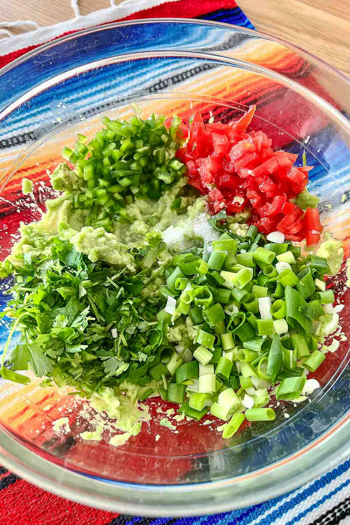 Ingredients diced for guacamole in a glass bowl.