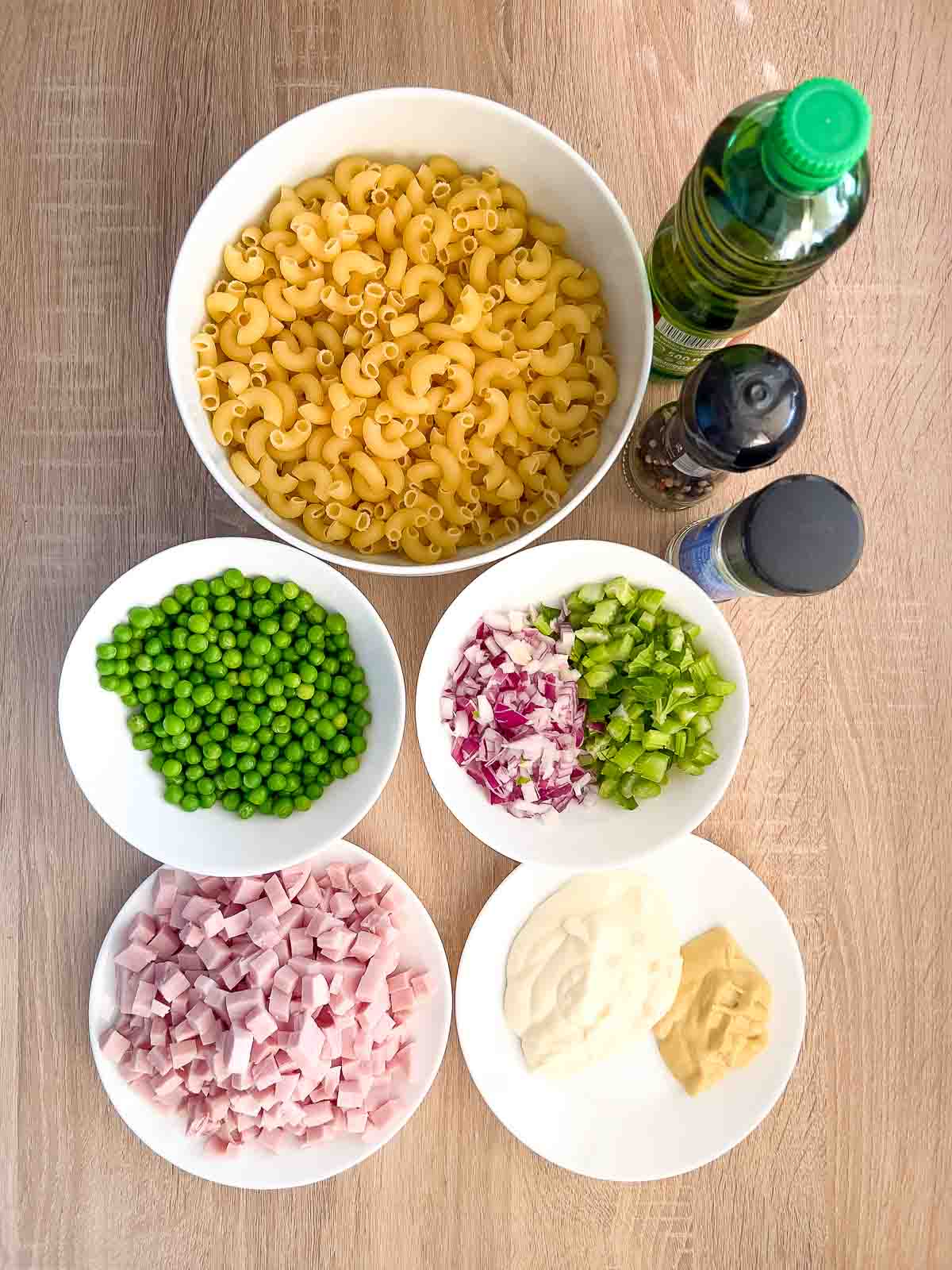 Ingredients display for pasta salad with ham on table.