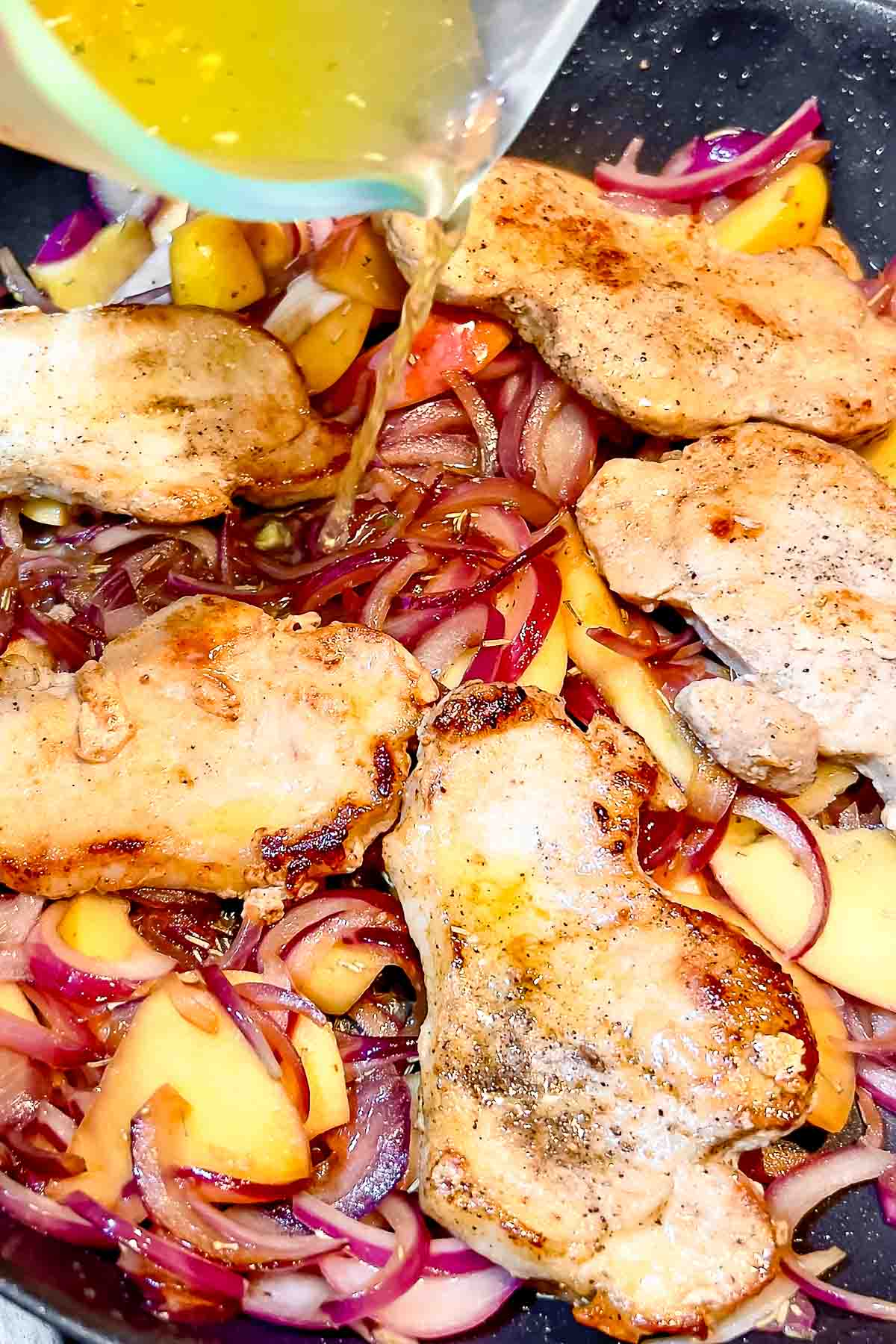 Adding chicken broth to the dish.