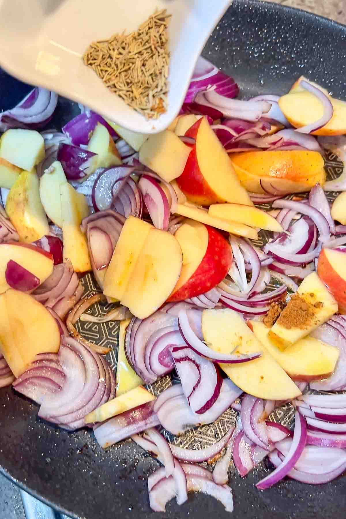 Adding rosemary and cayenne pepper to the apples and onions.