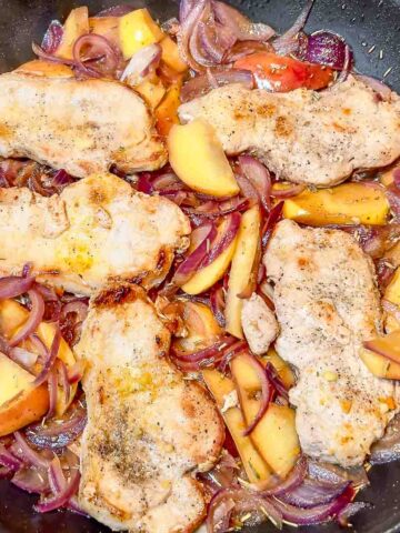 Pork Loin Slices with Onions and Apples in a skillet.