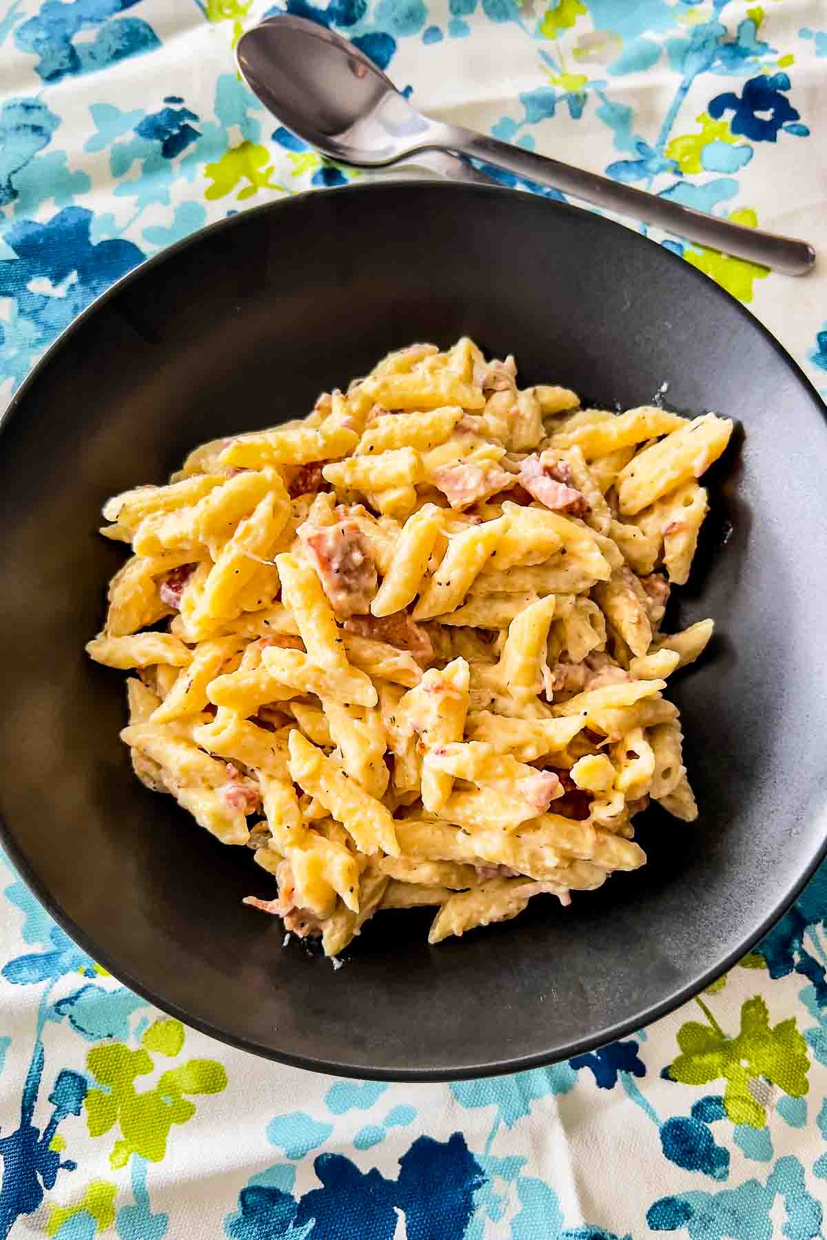 Stove Mac And Cheese With Ham on a black bowl with kitchen towel.