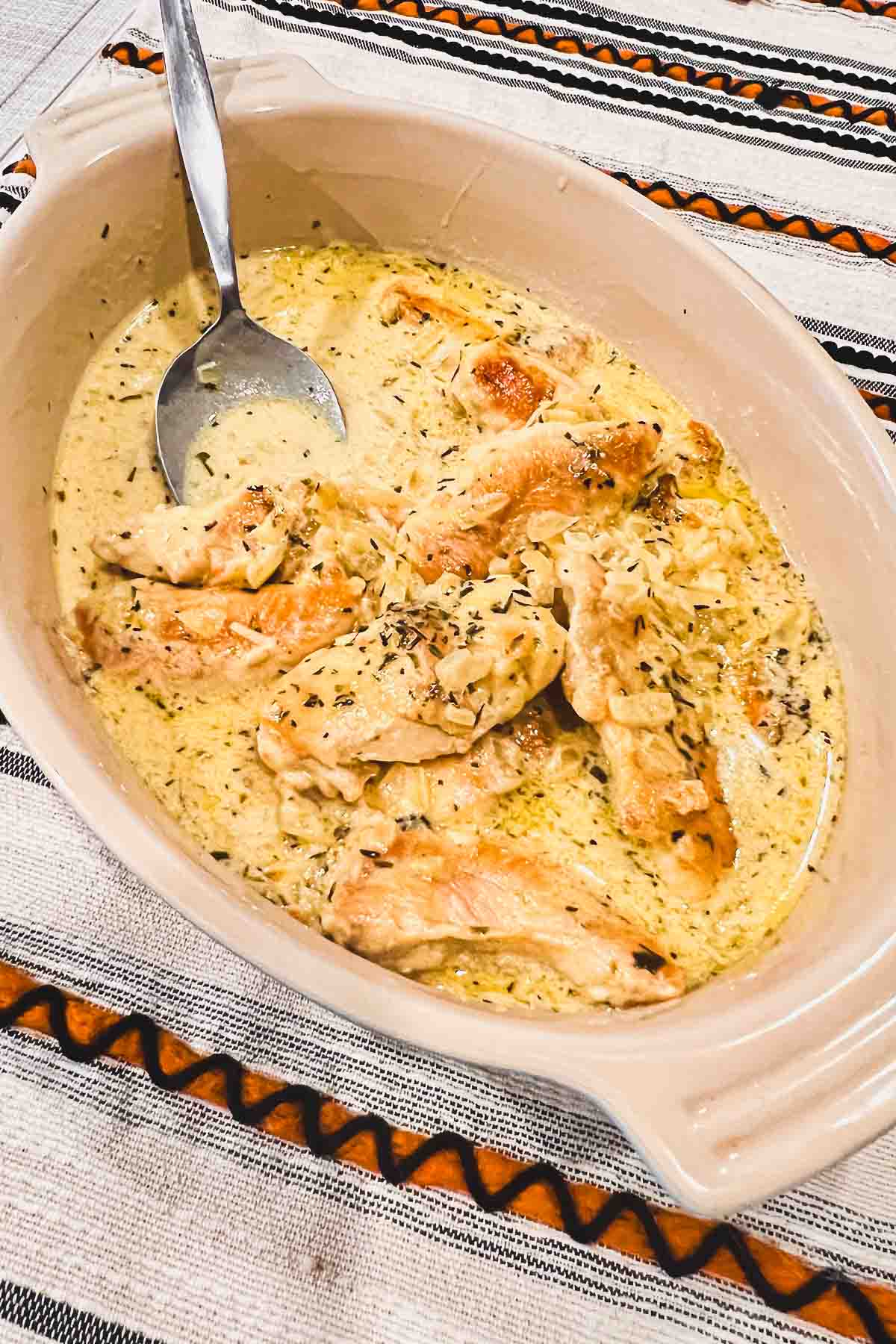 Chicken in mustard sauce in a serving dish with spoon.