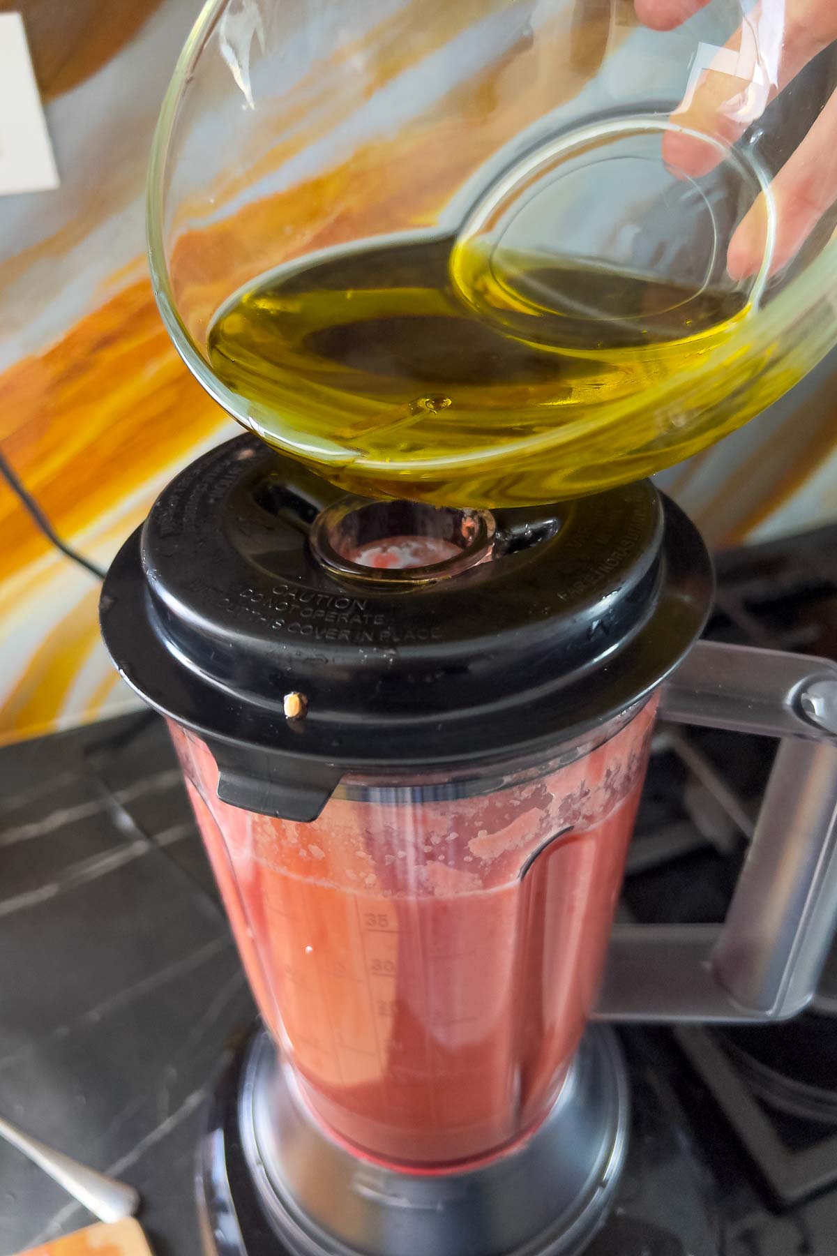 Adding olive oil to the blender.