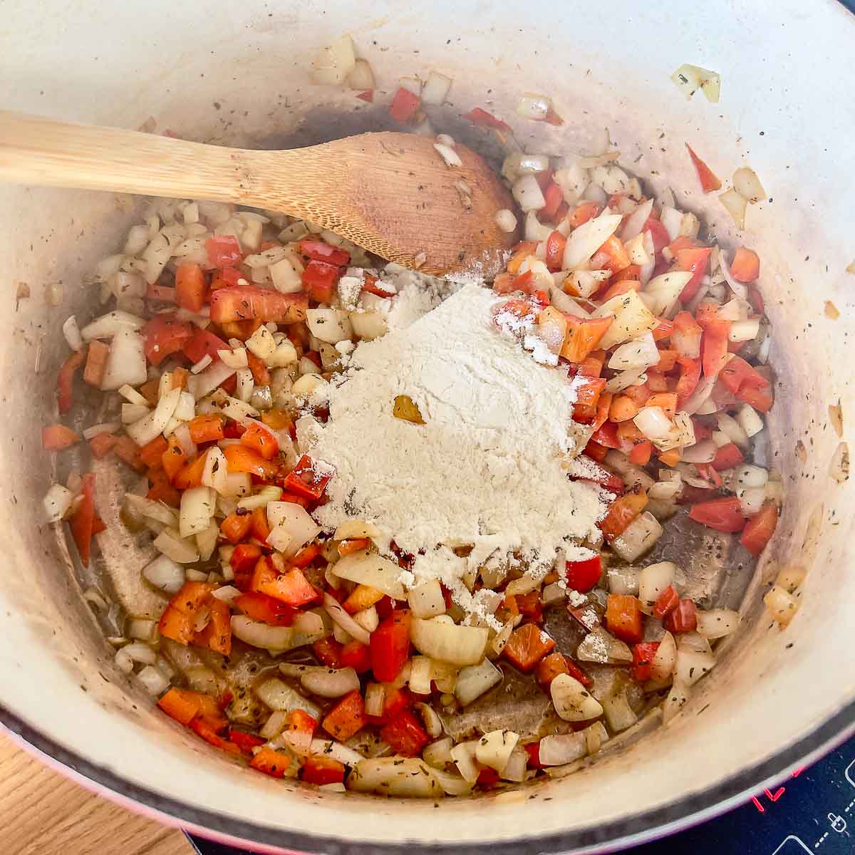 Adding flour to the vegetables.